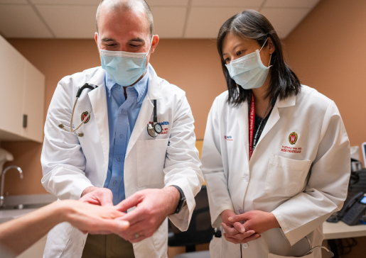 Rheumatology fellow Dr. Brad Bohman examines a patient while fellowship director Dr. Tiffany Lin oversees