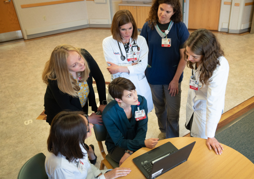 Faculty and learners in the Division of Geriatrics and Gerontology converse around a laptop.