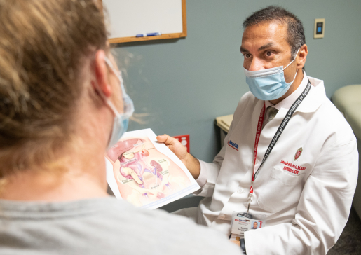 Dr. Sandesh Parajuli showing an anatomical diagram to a patient in the transplant clinic