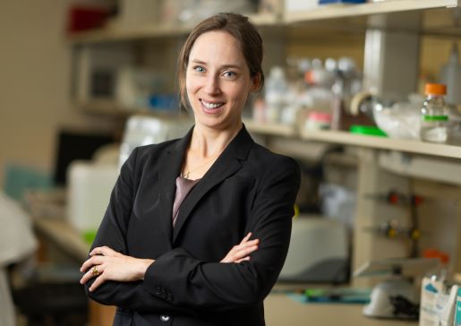 Dr. Sara McCoy in a black jacket with arms crossed in her lab