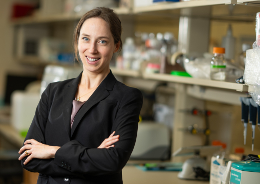 Dr. Sara McCoy in a black jacket with arms crossed in her lab