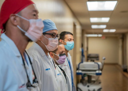 Four members of the interventional nephrology team in scrub caps and masks standing alongside a wall at University Hospital