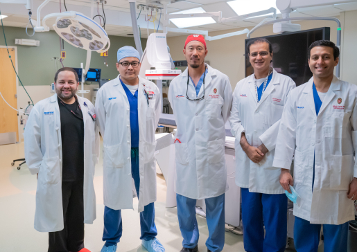 Five members of the interventional nephrology team standing side-by-side in a procedure room