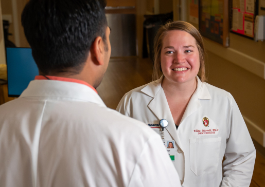 Nephrology PA Eliza Harrold smiles while talking to Dr. Roy Jhagroo in a hallway at University Hospital