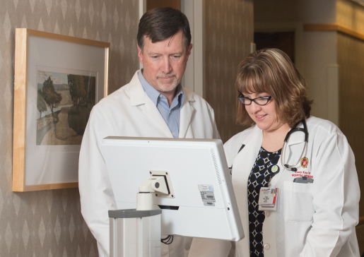 Dr. Scott Wilson and Casey Ray, NP, looking at a computer screen in the hallway at University Hospital