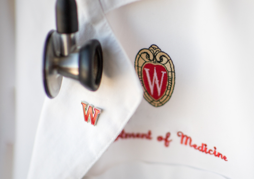 A white lab coat with Department of Medicine stitched in red under the UW–Madison crest.