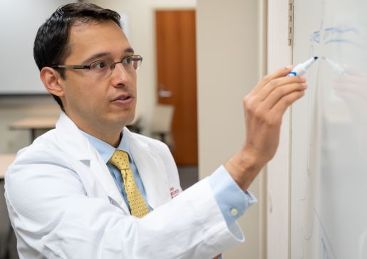 Dr. Luis Lomeli writes on a whiteboard in a conference room