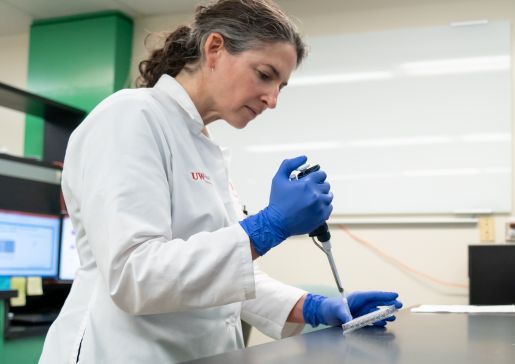 Side photo of Dr. Miriam Shelef using a pipette in the lab