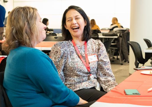 Staff members Tia Juni and Sheri Lawrence laugh together at a department awards event