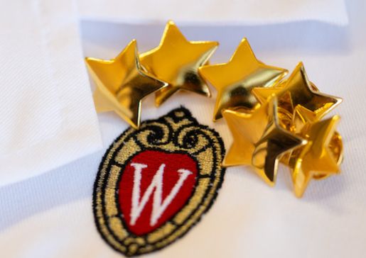 Closeup of white coat lapel with gold award stars
