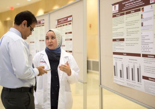 Learner and faculty member talk at a department poster session