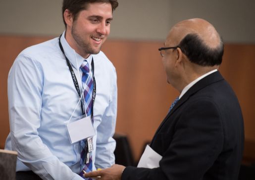 Adam Gepner shaking hands with Dr. Sanjay Asthana at a conference