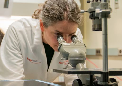 Miriam Shelef, MD, PhD, associate professor, Rheumatology, examines slides under a microscope.