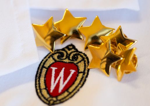 Close-up photo of the UW crest and golden stars on the front of a white lab coat.