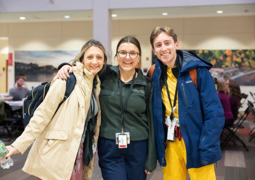 Three doctors stand together, smiling at the camera