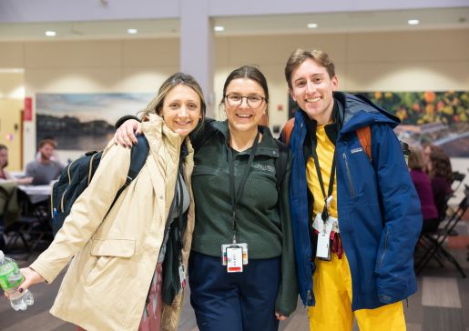 Three doctors stand together, smiling at the camera
