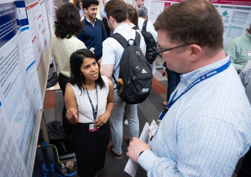 A woman speaking to a man at a poster session