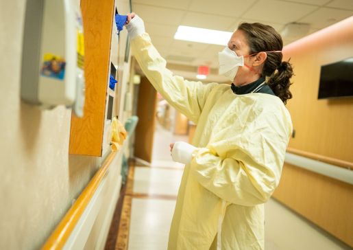 A physician getting gloves from a dispenser in the hospital.