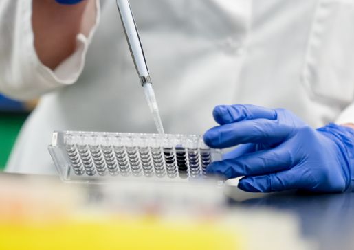 Closeup of gloved hands with a pipette in a lab
