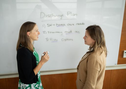 Sara Westergaard and another person talking in front of a white board.