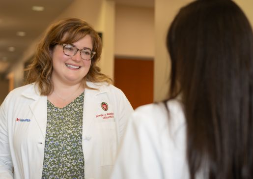 Two female doctors in white coats speaking a clinic hallway