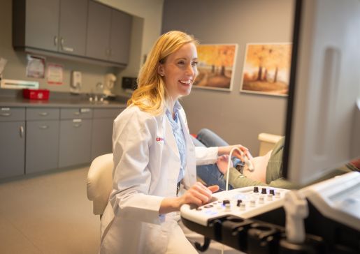 Dr. Megan Lutz in a clinic room giving a simulated patient an abdominal ultrasound