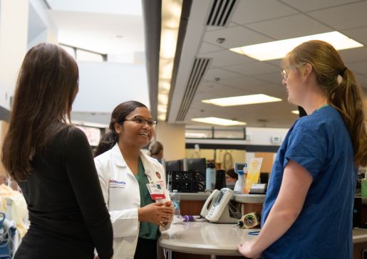 Dr. Kavya Kommaraju talking to medical staff in a hospital hallway.