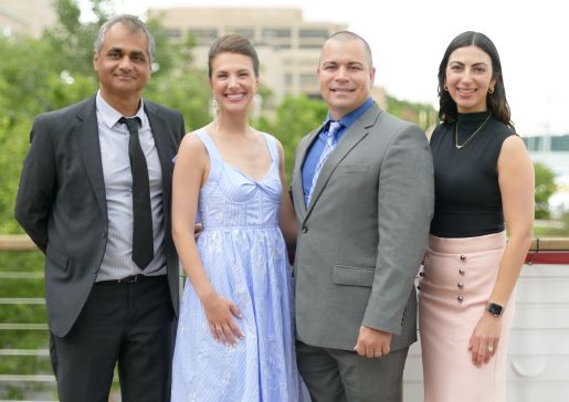 Four people in formal dress standing in a line for a group photo.