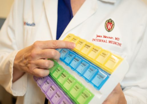 Dr. Joan Neuner points to a pill organizer.