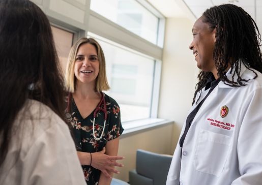 Three doctors speaking in a clinic hallway