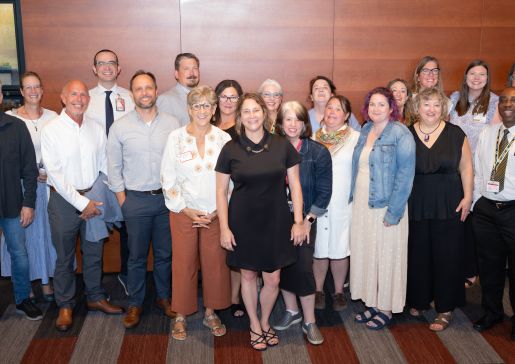 Sheri Lawrence (center) smiles with nearly 20 of her current and former direct reports at a recent gathering to celebrate her retirement. 